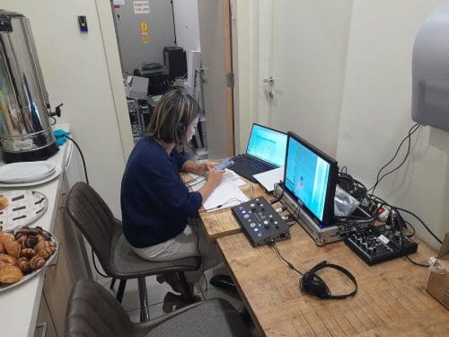 מתרגמת יושבת מול מחשב וציוד של תרגום סימולטני